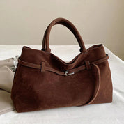 Brown suede shoulder bag on bed