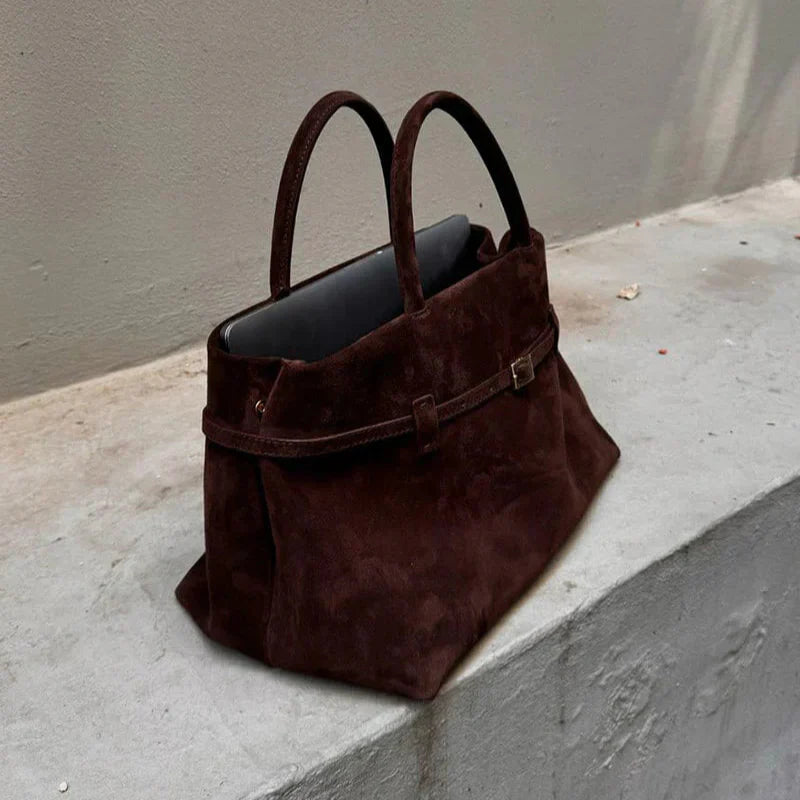 Brown suede shoulder bag on concrete ledge