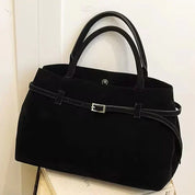 Black suede shoulder bag on books