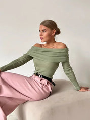 Green off-shoulder ribbed sweater seated pose