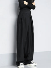 Zwarte wijde broek met hoge taille en witte sneakers detail shot
