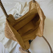Woven straw tote bag with tassel, open showing interior, close-up