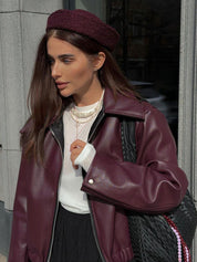 Oversized faux leather jacket maroon worn with pearl necklace