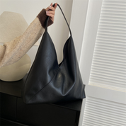 Black vegan leather shoulder bag held by hand