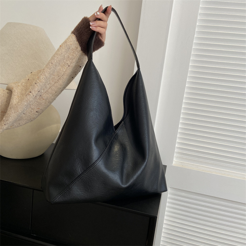Black vegan leather shoulder bag held by hand