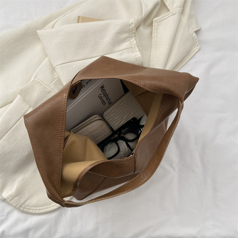 Brown vegan leather shoulder bag open, showing interior and contents