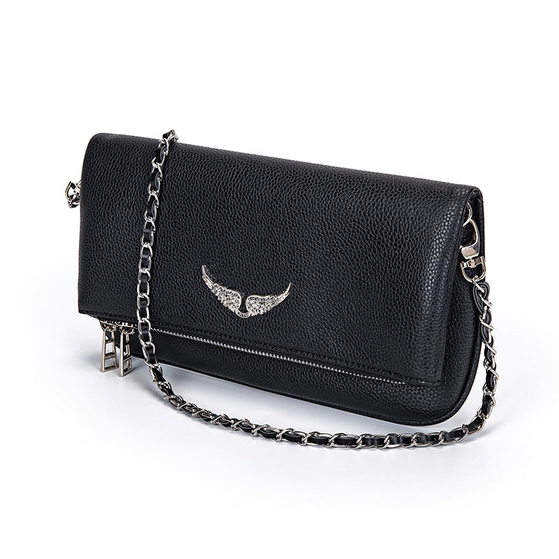 Black leather clutch with silver chain and wing embellishment, angled view