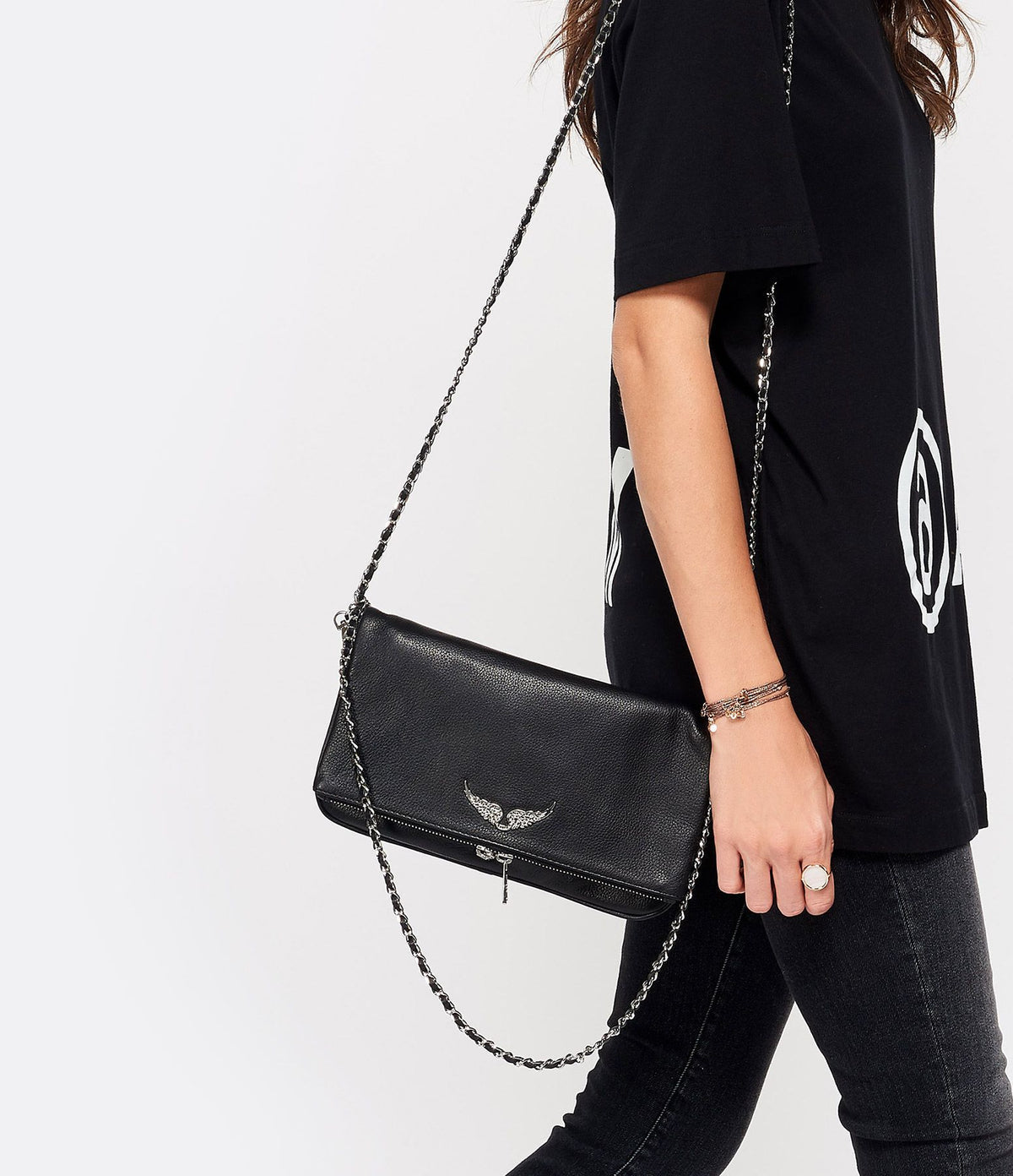 Black leather clutch with silver chain worn over shoulder, model view
